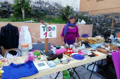 Usmívající se paní na bleších trzích před stánkem u kterého je napsáno "vše za 1 euro"